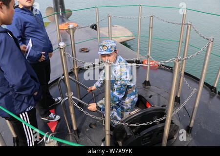 Eine chinesische Marine Soldat führt Touristen nach unten in einen stillgelegten Typ-091 Atom-U-Boot auf dem Display zu klettern an der Chinesischen Marine Museum in Qingdao Stockfoto