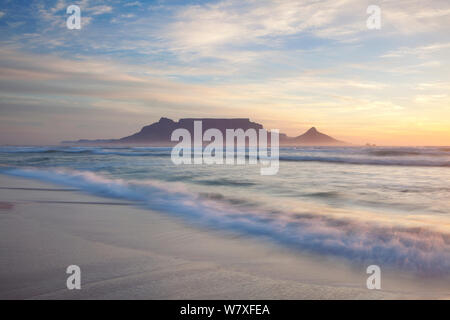 Wave waschen über Strand bei Sonnenuntergang mit dem Tafelberg im Hintergrund. Bloubergstrand, Kapstadt, Südafrika. November 2011. Nicht-ex. Stockfoto