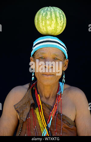 Portrait von naro San Frau in traditioneller Kleidung und Stirnband, Balancing Kürbis auf dem Kopf, Kalahari, Ghanzi region, Botswana, Afrika. Oktober 2014. Stockfoto