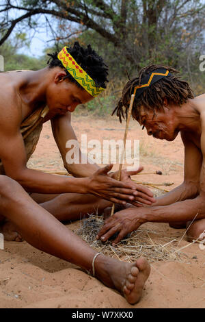 Naro San Buschmännern Feuer machen durch Reiben stick, Kalahari, Ghanzi region, Botswana, Afrika. Trockene Jahreszeit, Oktober 2014. Stockfoto