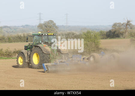 Buckingham, Großbritannien - 01 April, 2019. Ein John Deere Traktor pflegt Land während einer Dürre mit einem Cambridge Walze oder cultipacker. Buckingham, Großbritannien Stockfoto