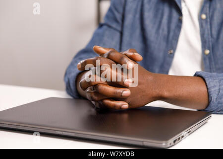 Nahaufnahme der afrikanischen Mann am Tisch sitzen mit geschlossenen Laptop Stockfoto