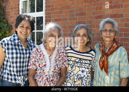 Buckingham, Großbritannien - 05.Juli 2019. Drei ältere indische Frauen stellen mit einer Tochter lächelnd für ein ehrliches Porträt an einer Wiedervereinigung in Großbritannien. Stockfoto