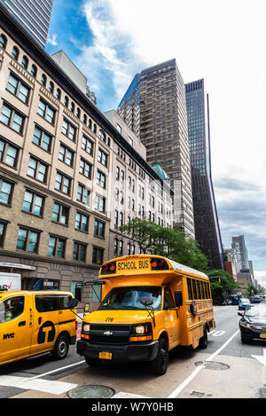 New York City, USA - 2. August 2018: Yellow School Bus und Taxi auf einer Straße in Midtown Manhattan, New York City, USA Stockfoto