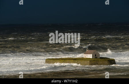 Wellen, die auf die kleine Kapelle von Porth Cwyfan während Sturm, Anglesey, Wales, Mai 2012. Stockfoto