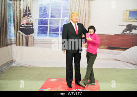 Ein chinesischer Besucher nimmt Fotos mit einer Wachsfigur des neuen amerikanischen Präsidenten Donald Trump auf ein Wachsfigurenkabinett in Shenyang City, im Nordosten Chinas Stockfoto