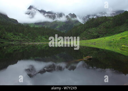 Noch See mit Berge in Nebel gehüllt, Berg Kawakarpo, Meri Snow Mountain National Park, Provinz Yunnan, China. Stockfoto