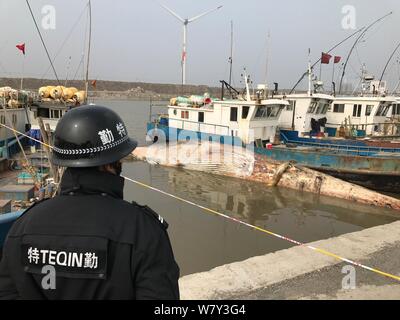 Ein Polizist wacht außerhalb einer abgesperrten Bereich die Toten Bartenwal ohne Kopf und Flossen im Stadtteil Pudong, Shanghai, China, 2 gefunden Stockfoto