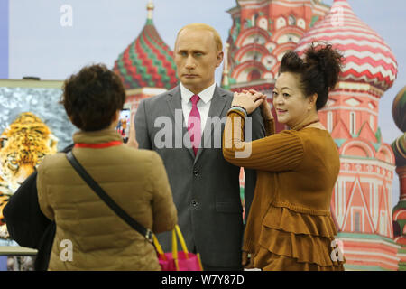 Ein Besucher stellt für Fotos mit einer Wachsfigur des russischen Präsidenten Wladimir Putin auf dem Display während einer Ausstellung in Shenyang City, im Nordosten Chinas L Stockfoto