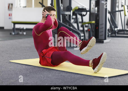 Junge Sportler tun Magen trainieren Sie im modernen Fitnessraum Stockfoto