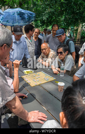 Xiangqi, Ansicht der Männer, die ein Spiel von Xiangqi, auch als chinesisches Schach bekannt, im Columbus Park im Chinatown-Viertel von New York City, USA beobachten Stockfoto