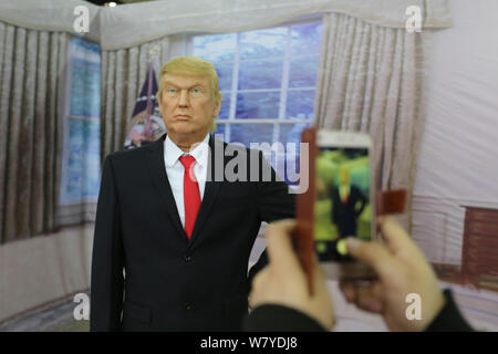 Ein Besucher nimmt Fotos mit einer Wachsfigur des neuen US-Präsidenten Donald Trump auf dem Display während einer Ausstellung in Shenyang City, im Nordosten der chinesischen Provinz Liaoning Stockfoto