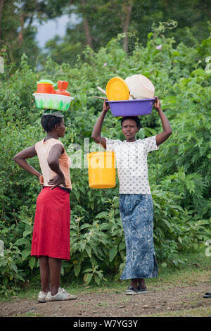 Frauen, die miteinander sprechen, während die Kunststoff Körbe auf dem Kopf, das Mfangano Island, Lake Victoria, Kenia, Februar 2013. Stockfoto