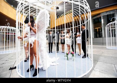 Künstler Flügel tragen sind in riesigen Vogelkäfige während einer Flash Mob für die Bürger zu nennen sich selbst vom Leben in der Stadt am Goldenen Hongqia zu befreien beschränkt Stockfoto