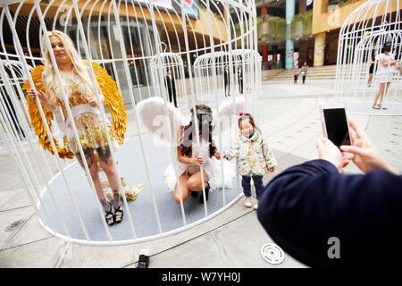Künstler Flügel tragen sind in riesigen Vogelkäfige während einer Flash Mob für die Bürger zu nennen sich selbst vom Leben in der Stadt am Goldenen Hongqia zu befreien beschränkt Stockfoto
