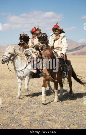 Zwei Adler Jäger auf Mongolische Pferd geht mit ihren weiblichen Steinadler (Aquila Chrysaetos) während der Adler Jäger Festival, in der Nähe von Sagsai, Bayan-Ulgii Aymag und Mongolei. September 2014 .. Stockfoto