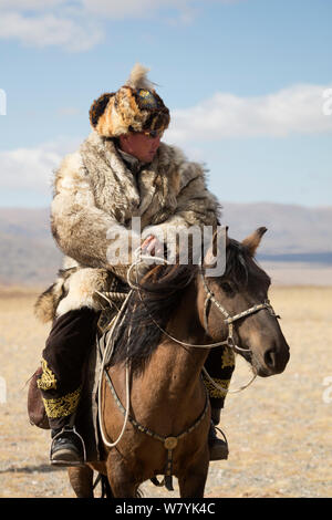 Eagle Hunter montiert auf Mongolische Pferd am Adler Jäger Festival, in der Nähe von Sagsai, Bayan-Ulgii Aymag und Mongolei. September 2014 .. Stockfoto