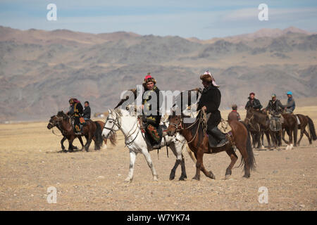 Adler Jäger montiert auf Mongolische Pferde kommen mit ihren weiblichen Steinadler (Aquila Chrysaetos) konkurrieren auf dem Adler-Jäger-Festival in der Nähe von Sagsai, Bayan-Ulgii Aymag, Mongolei. September 2014... Stockfoto