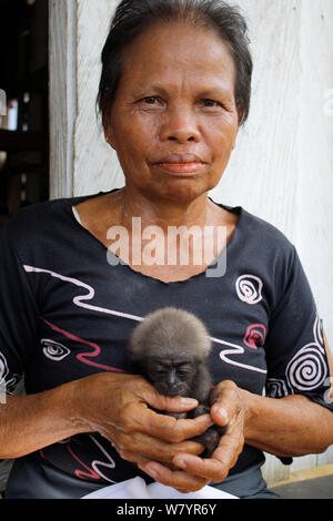 Frau mit Orphan baby Gibbon (Hylobates), deren Mutter in Palmölplantage getötet wurde, Süd Kalimantan, indonesische Borneo. August 2010. Stockfoto