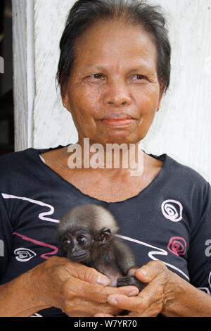 Frau mit Orphan baby Gibbon (Hylobates), deren Mutter in Palmölplantage getötet wurde, Süd Kalimantan, indonesische Borneo. August 2010. Stockfoto