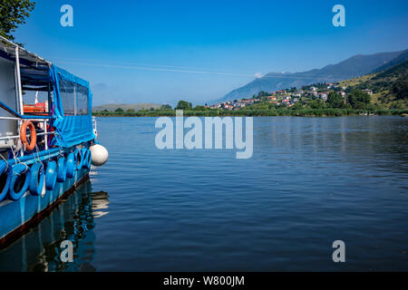 Village Lake gerahmte Blick durch kleine touristische Cruise weiß und blau Anlegestelle am See Pamvotida in der Nähe der wunderschönen kleinen griechischen Stadt. Am frühen Morgen spri Stockfoto