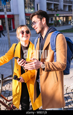 Glückliches Paar mit Fahrrad und Smartphone in der Stadt Stockfoto