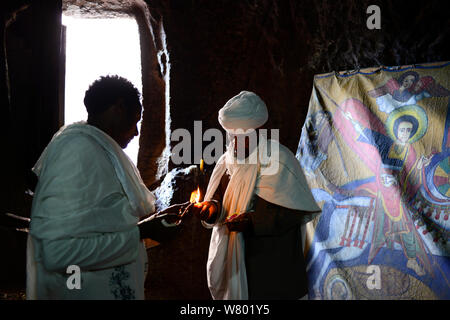 Frommer Christ im traditionellen robess Beleuchtung Kerze vor Wette Danaghel (Teil der nordwestlichen Gruppe von Kirchen in Lalibela). UNESCO-Weltkulturerbe. Lalibela. Äthiopien, Dezember 2014. Stockfoto