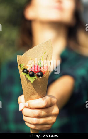 Mädchen hält eine Papiertüte mit Beeren, close-up Stockfoto