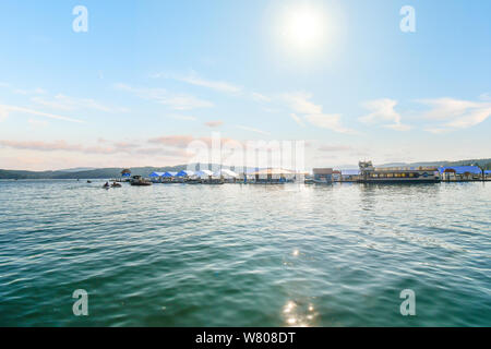 Die heiße Sonne beginnt vor über einem See Marina und Dock auf Lake Coeur d'Alene, Idaho, Touristen und Einheimische Wassersport, Boote und Jetskis genießen Stockfoto