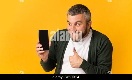 Super glücklich bärtiger Mann, Smartphone, Daumen nach oben zeigt Stockfoto