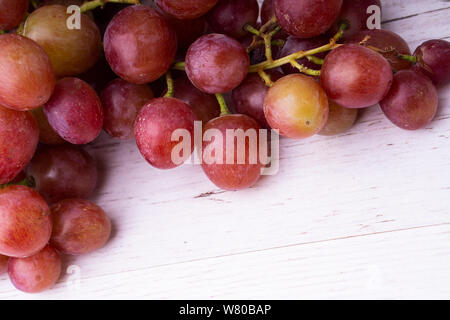 Ein Bündel von rosa Trauben auf einem natürlichen Holz- licht Arbeitsplatte. Stockfoto