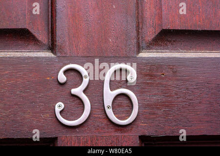 Haus Nummer 36 in silber Metall Ziffern auf einem roten Holztür aus Kirschholz Stockfoto