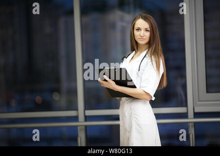 Medizin. Ärztin lächelt. Praxis im Krankenhaus. Hausarzt. Eine junge Frau ist schön. Hinweise geben Stockfoto