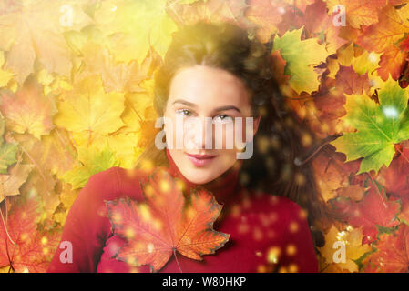 Mädchen mit roten Ahorn Blatt in der Hand über bunte Laub Hintergrund. Gold gemütliche Herbst Konzept. Ansicht von oben. Kopieren Sie Platz für Werbung. Sonnigen Tag, Stockfoto