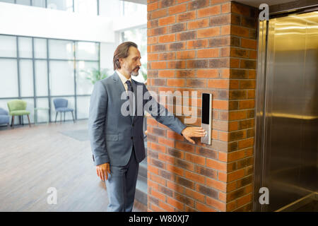 Unternehmer tragen graue Anzug und Krawatte stehen in der Nähe des Aufzugs Stockfoto