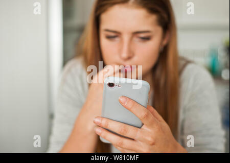 Brunette jugendlicher Mädchen auf den Bildschirm Ihres Smartphones Stockfoto