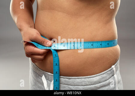 Übergewichtige Frau mit Maßband um den Bauch Stockfoto