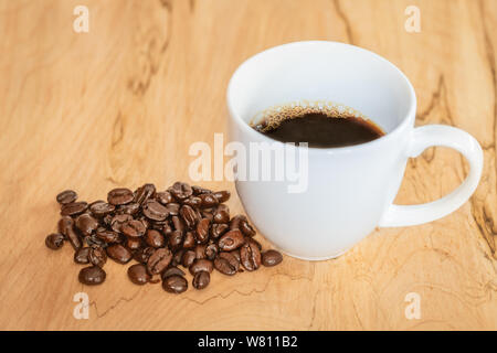 High Angle Shot aus einem Bündel von Kaffeebohnen durch eine Tasse Kaffee Stockfoto