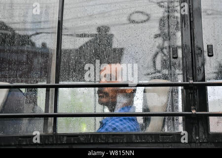 Ein Mann schaut durch die halbe verschwommene Scheibe eines Busses mit Regen fällt während eines regnerischen Tag in Kalkutta. Gangetic West Bengalen, der zum größten Teil aus Kolkata ist die derzeit am meisten Regen mangelhaft Region des Landes mit einem Mangel von 47%. Stockfoto