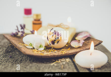 Verschiedene Whirlpool Produkte auf braunem Holz- fach cremige Badebombe, natürliche Seife mit Baumwolle string, getrocknete Blütenblätter, Wellness Kerzen, wesentliche Stockfoto