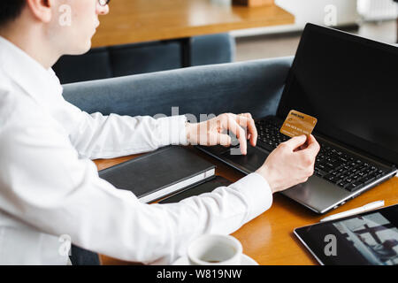 Seitenansicht Erntegut Hände mit einem Gold Kreditkarte und einen Laptop. Stockfoto