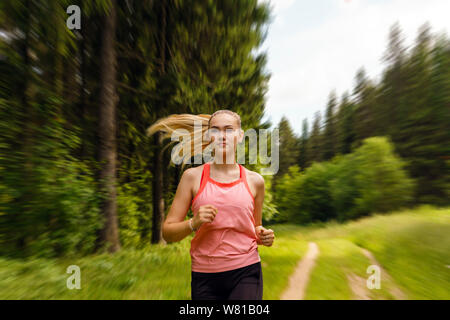 Junge Frau Joggen durch einen sonnigen Wald Stockfoto