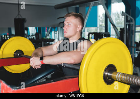 Athlet Pause zwischen den Sätzen der Hantel Übungen in eine Maschine mit Gewichten an der Turnhalle Stockfoto