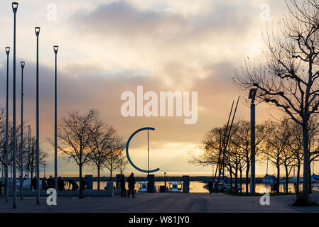 Silhouette Sonnenuntergang am Genfer See und Leute genießen, Aktivitäten im Freien an der Promenade am Wasser mit Hintergrund der Bahndamm und E skulpturale. Stockfoto