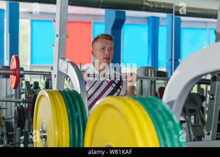 Junger Mann Aufwärmen ein barbell mit geringem Gewicht in der Turnhalle Stockfoto