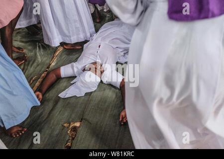 Eine Frau fällt nach einem Angriff aus dem Ritual Geister an einer lokalen Kirche in Kibera. Die traditionellen Glaubensvorstellungen und Praktiken der Afrikanischen Menschen sind eine Reihe von sehr unterschiedlichen Ansichten, die den verschiedenen ethnischen Religionen gehören. Viele Kenianer haben ihre eigenen Kirchen, die mit einer Mischung aus Christentum und traditionelle Religion, mit dem Ziel der Brandbekämpfung und Segen durch die rituelle spirituellen Glauben begonnen. Kirchen beginnen das Gebet Dienstleistungen in genau neun morgens um drei Uhr am Nachmittag jeden Sonntag und zielen auf eine Umwandlung von Gläubigen durch Gebete und der Heilige Geist. Jede Kirche Abo Stockfoto