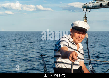 Alter Seemann auf seinem Segelboot gegen eine Marine Stockfoto