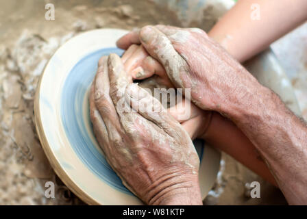 Zwei Paar Hände - männlich und weiblich, jung und alt - ein Ton auf der Töpferscheibe erstellen Stockfoto