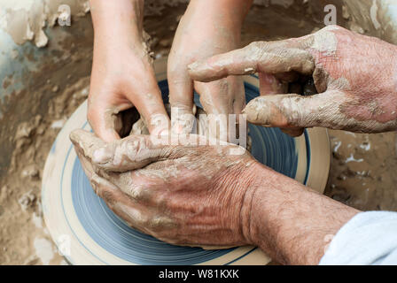 Zwei Paar Hände - Jung und Alt - Schimmel etwas aus Ton auf der Töpferscheibe Stockfoto