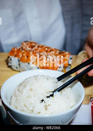 Vertikale Image der jungen Frau mit chinesischen Stäbchen Essen Maki Sushi japanische Küche Stockfoto
